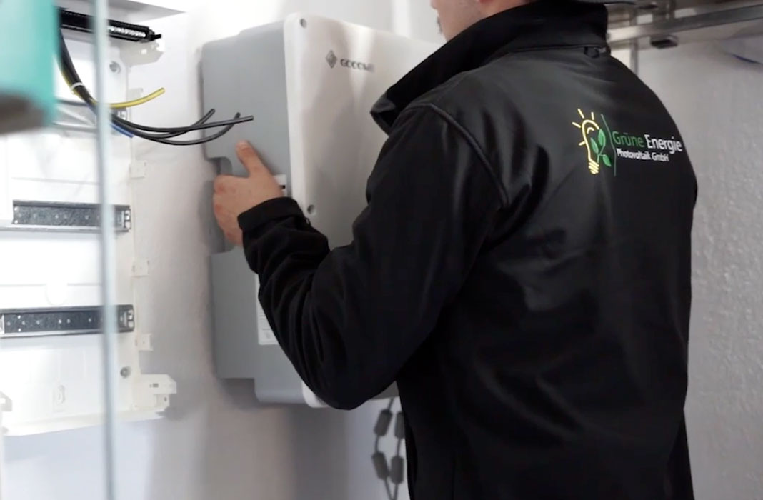 Handwerker der Grünen Energie hängt Wechselrichter auf